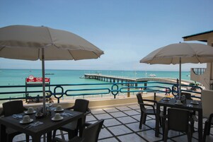 Un restaurante frente al mar con terraza, un muelle y vistas al océano.