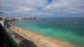 Un paisaje urbano costero con playa, edificios y una carretera.