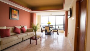 A living room with a sofa, coffee table, and a dining area with chairs and a table. - Blue Bay Hotel (Salinas)