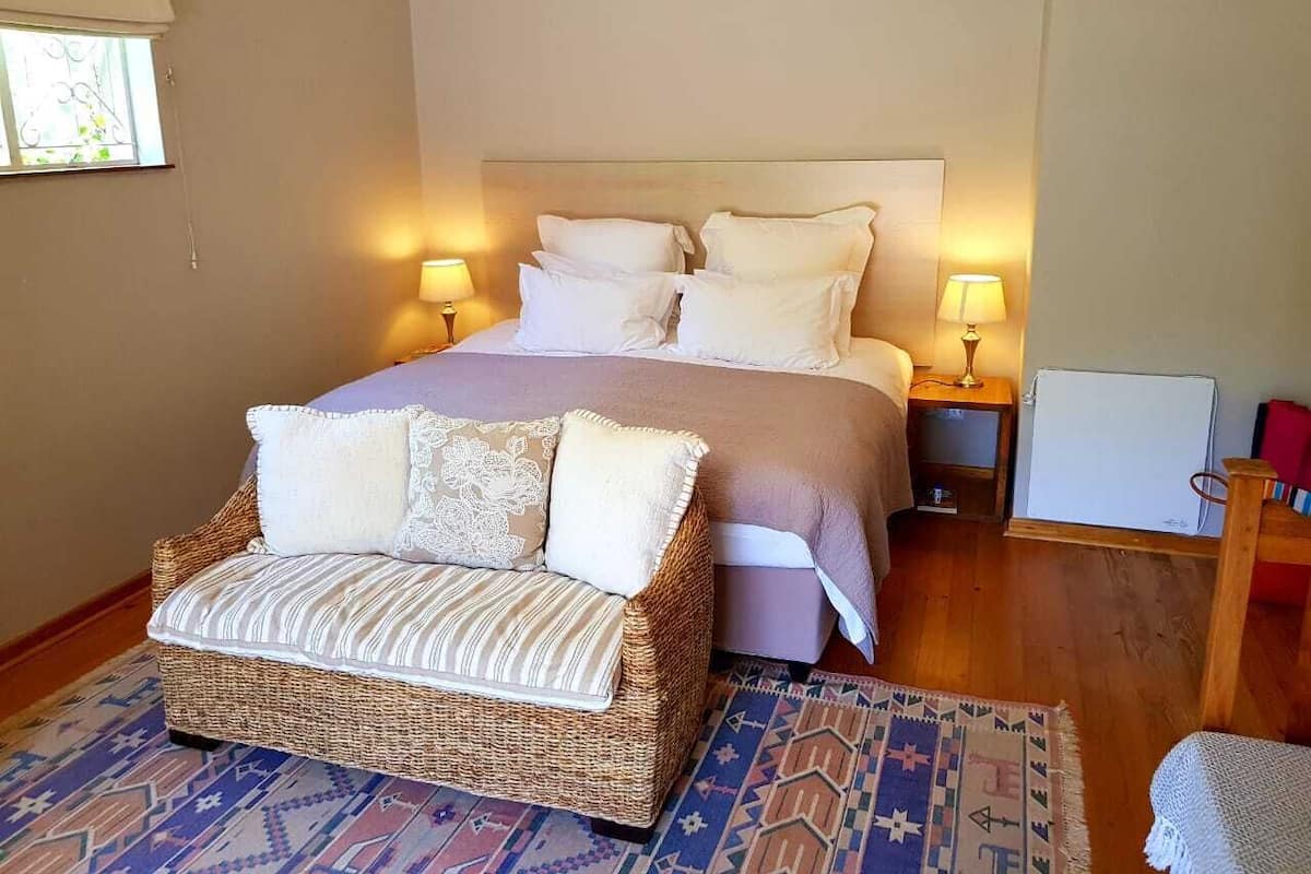A bedroom with a bed, two bedside tables, a wicker sofa, and a patterned rug.
