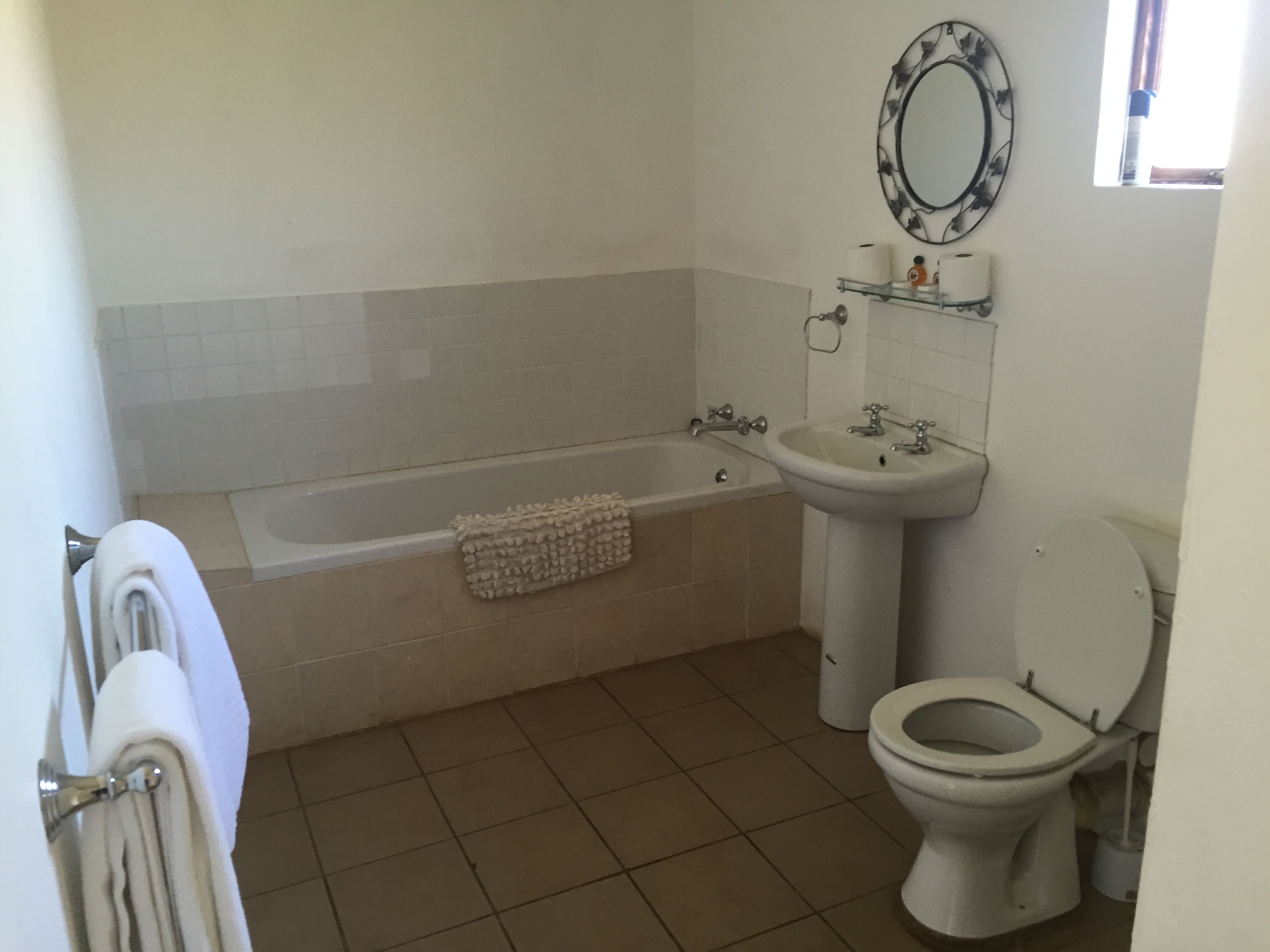 A bathroom with a bathtub, sink, toilet, and a mirror on the wall.