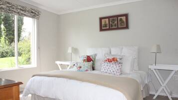 Un dormitorio con una cama grande, dos mesitas de noche, una ventana con cortinas y un cuadro enmarcado en la pared.