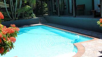 Una piscina rectangular con borde de azulejos, rodeada por un patio de ladrillo.