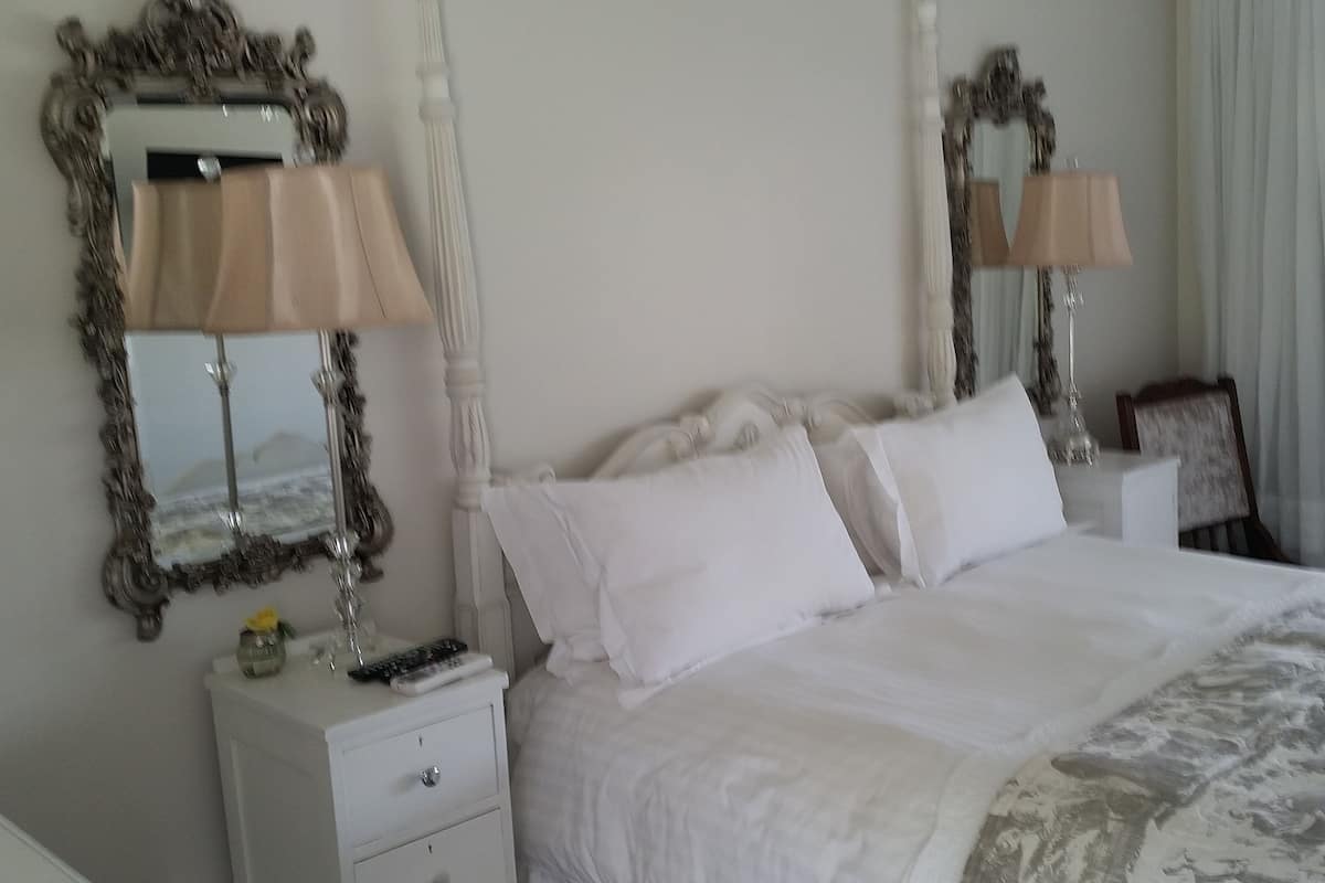 Une chambre d’hôtel avec un grand lit, deux tables de chevet, un miroir et une lampe.
