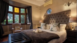Un dormitorio con una cama grande, una silla, una mesita de noche y una ventana con cortinas.