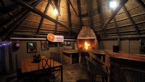 Una habitación estilo ático con chimenea de ladrillo, una mesa de madera y sillas de mimbre.
