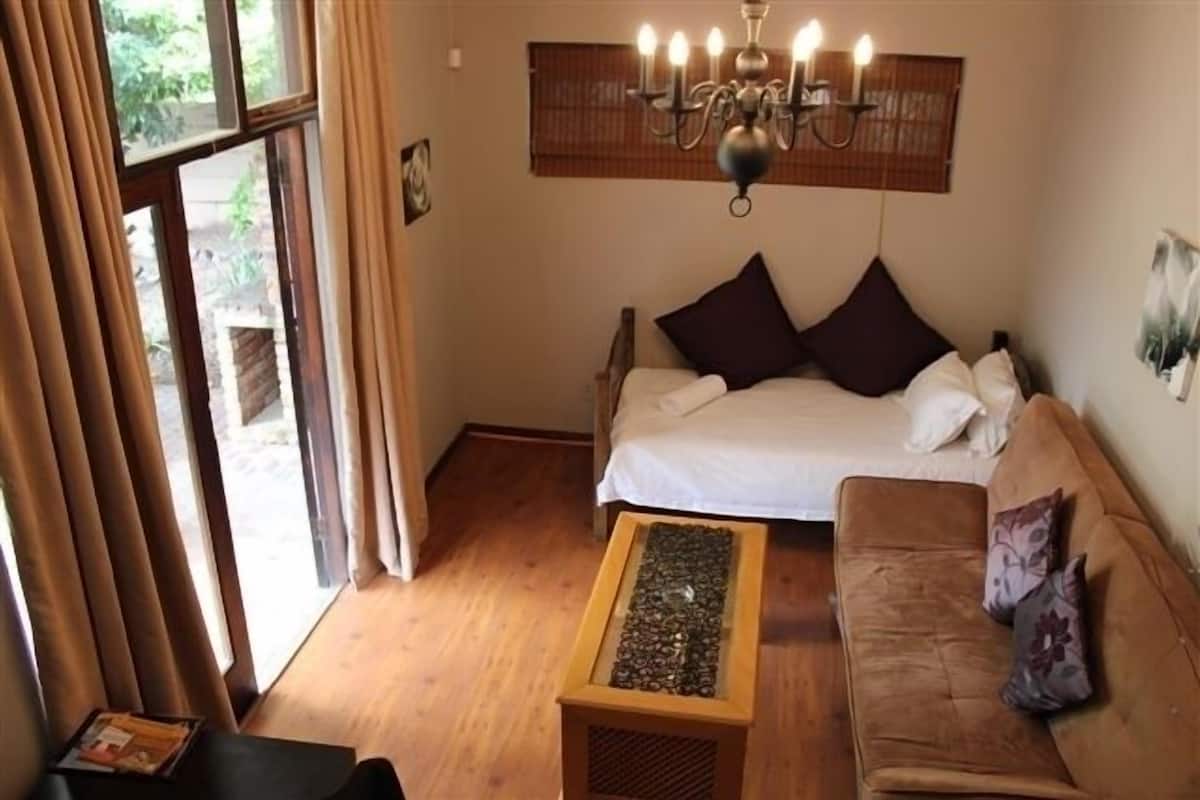 A cozy bedroom with a bed, a wooden coffee table, and a brown sofa.