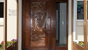 A wooden door with a detailed carving, a sign indicating 'Bed & Breakfast', and a small window with a view of the outside. - Lala Panzi B&B (Plettenberg Bay)
