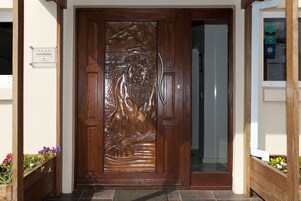 A wooden door with a detailed carving, a sign indicating 'Bed & Breakfast', and a small window with a view of the outside.