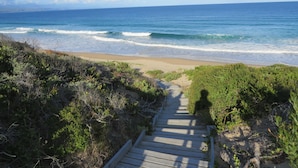 A wooden pathway leading to a beach with ocean views. - Lala Panzi B&B (Plettenberg Bay)