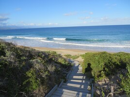 A wooden pathway leading to a beach with ocean views.