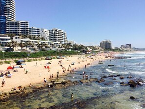 A beach with clear waters, rocky areas, and people enjoying the beach. - 203 Oyster Quays (Umhlanga)
