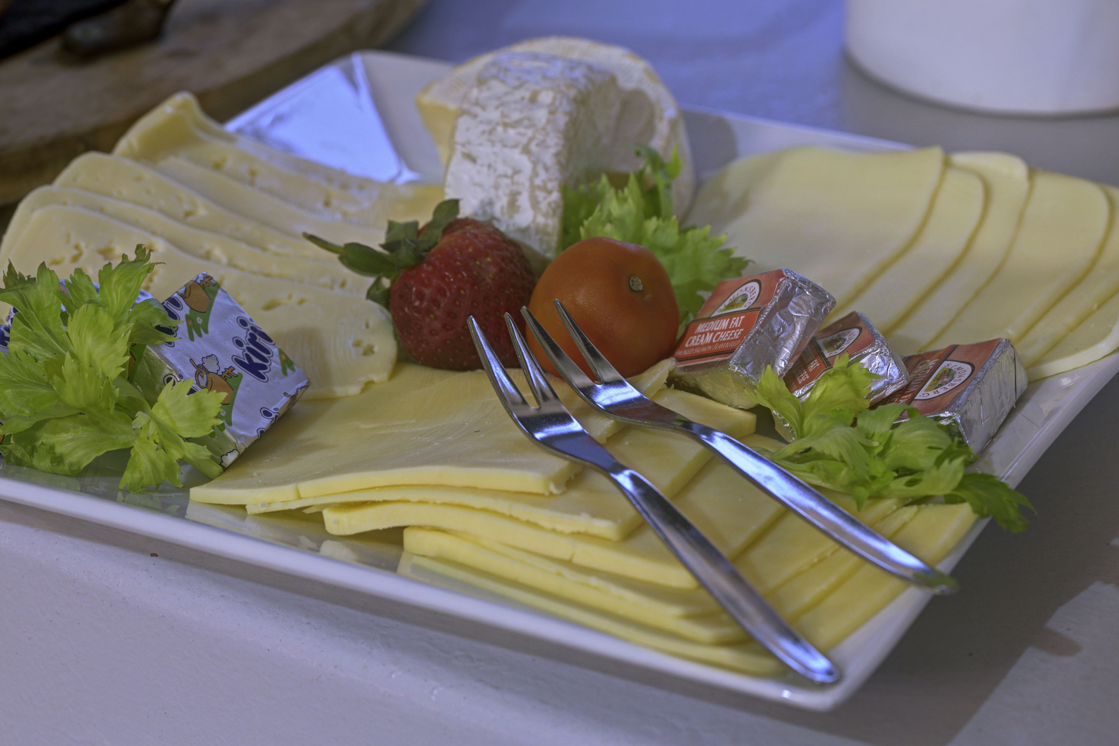 A cheese platter with various cheeses, fruits, and condiments.