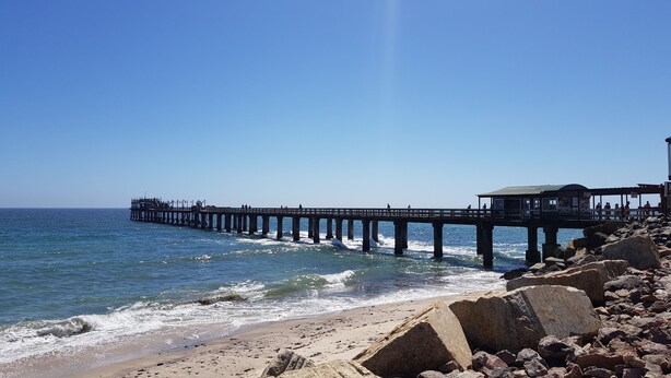A pier extending into the sea with a covered seating area and a building at the end. - Organic Stay Guesthouse (Swakopmund)
