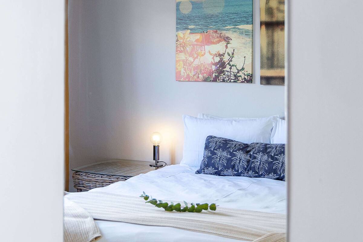 Une chambre à coucher avec un lit, un luminaire suspendu et deux tableaux accrochés au mur.