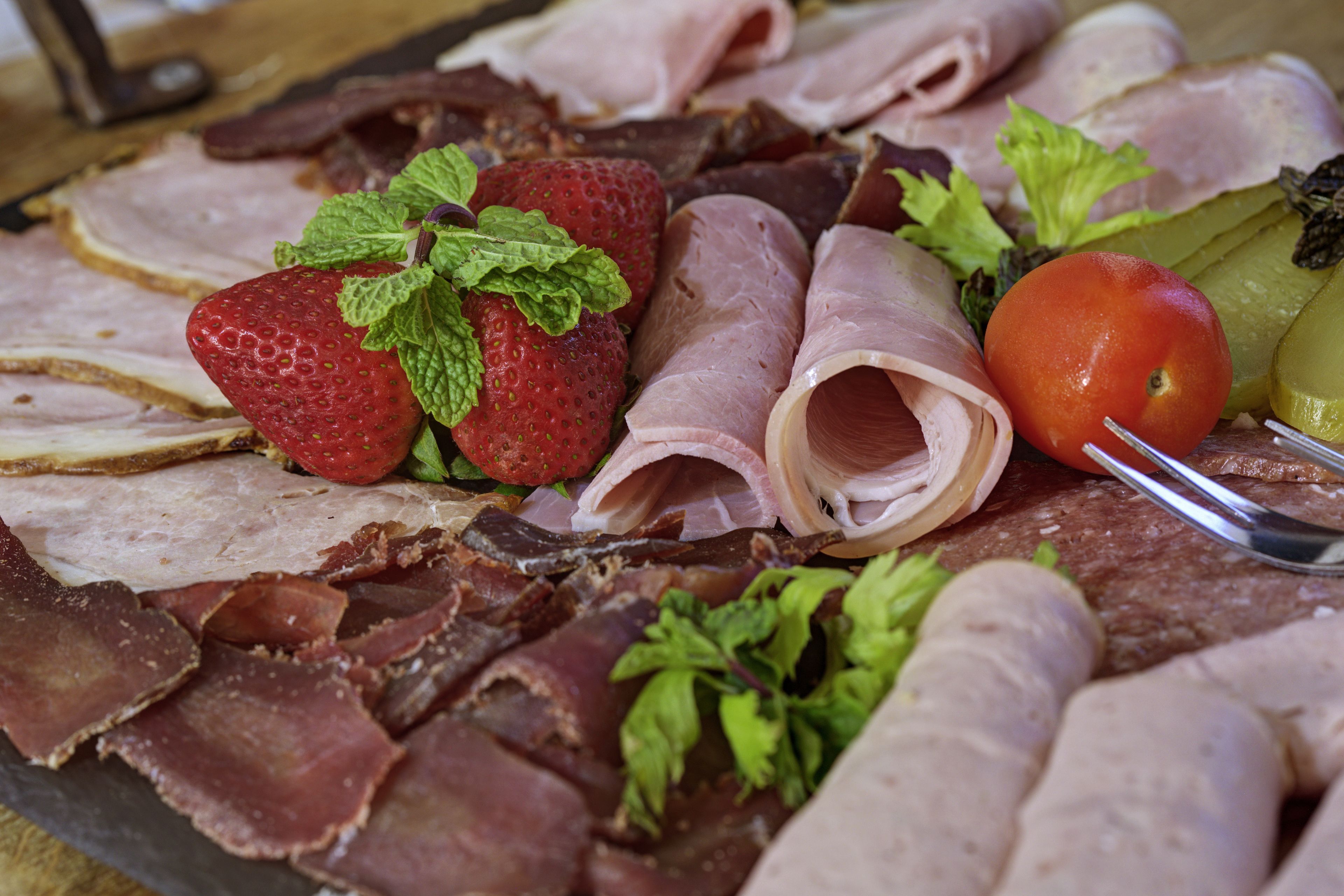 A variety of meats and fruits on a platter.