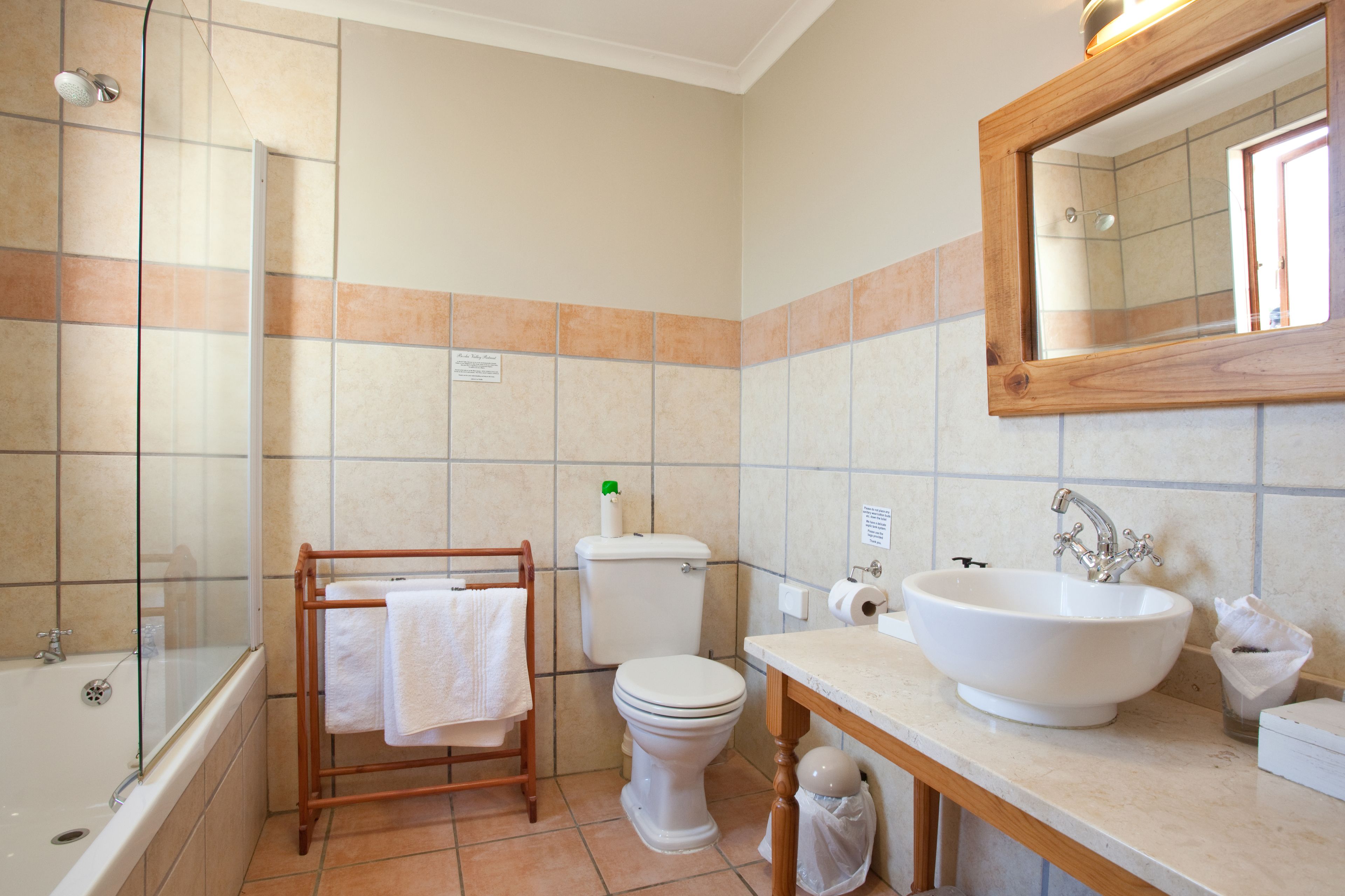 A bathroom with a bathtub, toilet, sink, and a wooden towel rack.