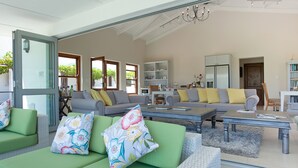 A spacious living room with a large sofa set, a dining table, and a kitchen area visible through an open door. - Dunstone Country House (Wellington)