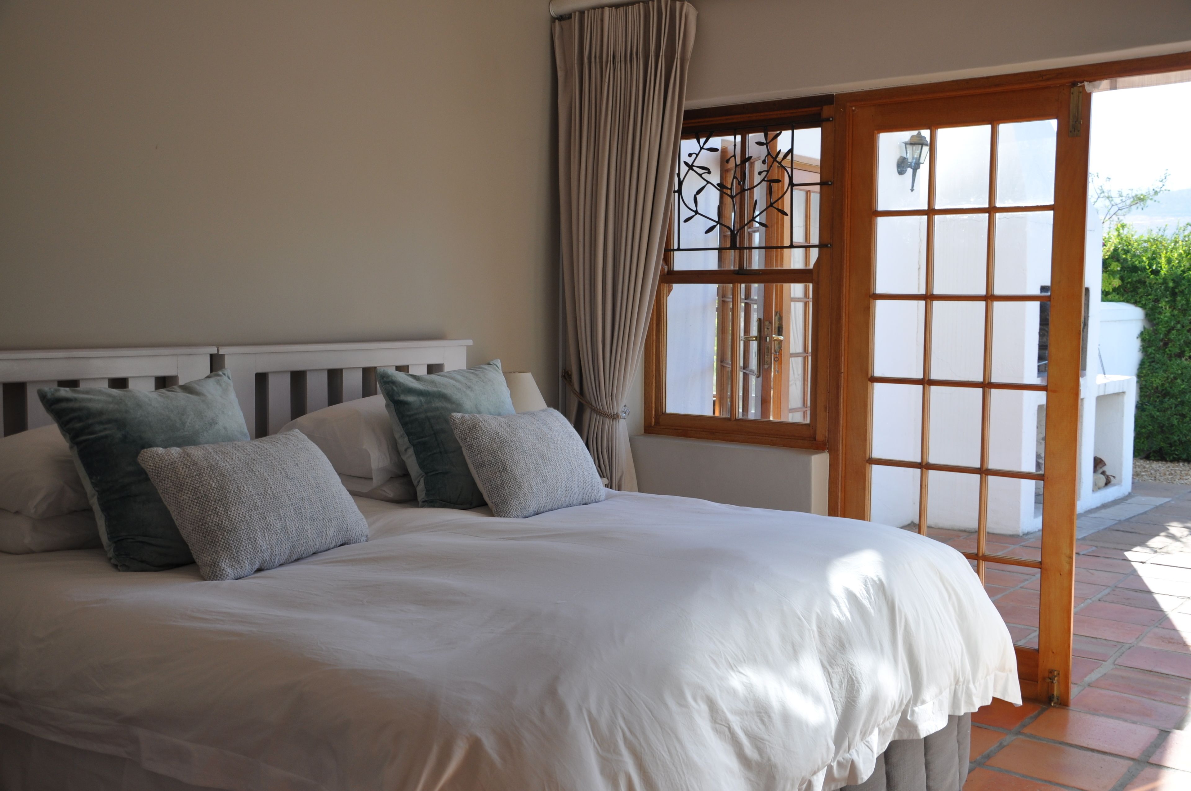 A bedroom with a large bed, a wooden headboard, and a view through a glass door to an outdoor area.