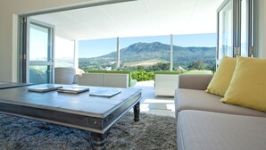 A modern living room with a large sliding glass door leading to a balcony with a mountain view. - Dunstone Country House (Wellington)