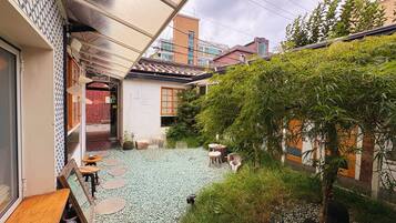 A courtyard with a tiled floor, outdoor seating, and a small tree.