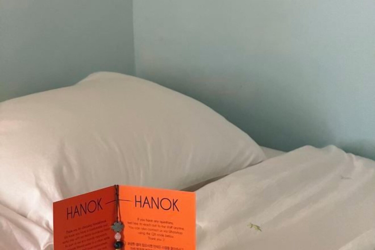 A book titled 'HANOK' on a bed with white bedding.