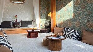 Een gezellige kamer met een bed, een houten bijzettafeltje en een behang met patroon.