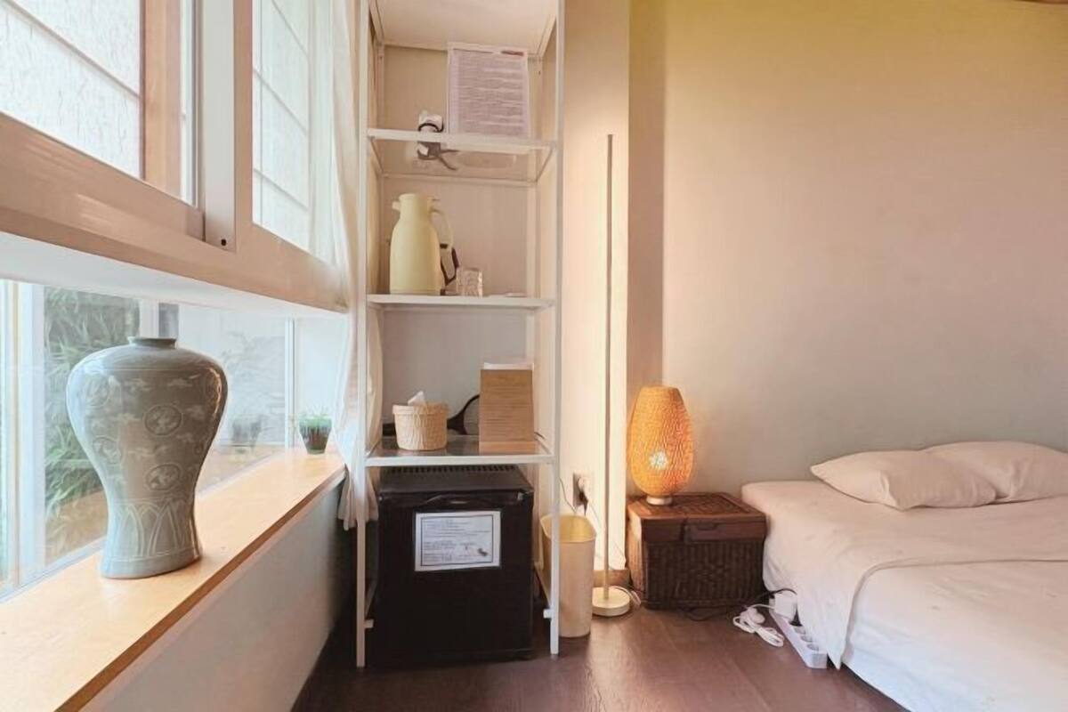 Une chambre à coucher avec un lit, une table de chevet, une lampe, un radiateur et une fenêtre donnant sur un beau paysage.