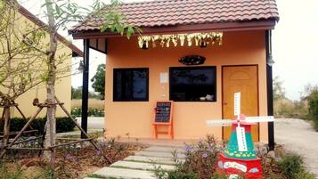 Situated in a natural setting, this charming building features a windmill and a dirt path leading to its entrance.