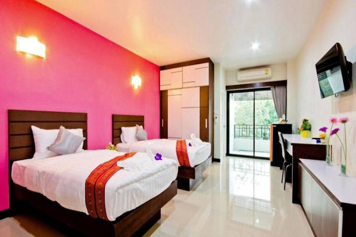 A hotel room with two beds, a desk, a TV, and a balcony with a view.