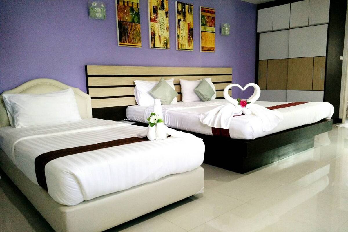 A hotel room with two beds, a wooden headboard, and a purple wall with artwork.