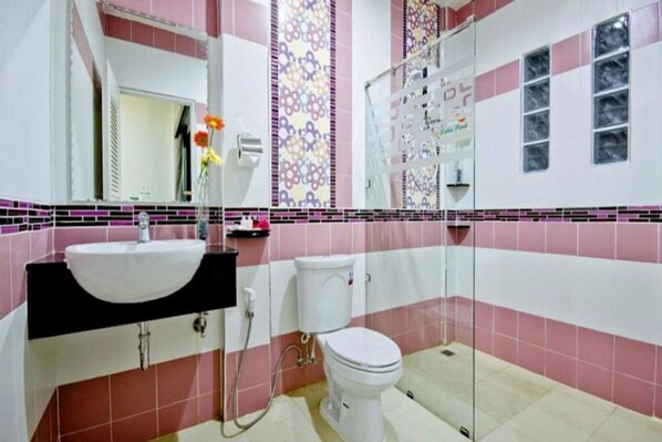 A bathroom with a white sink, toilet, and shower area.