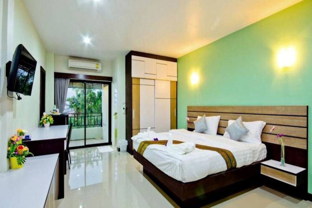 A hotel room with a bed, bedside tables, a desk, and a TV.