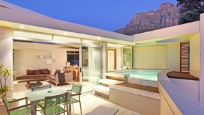 Ein moderner Außenbereich mit einer verglasten Terrasse, einer Sitzecke mit Tisch und Stühlen sowie einem Whirlpool.