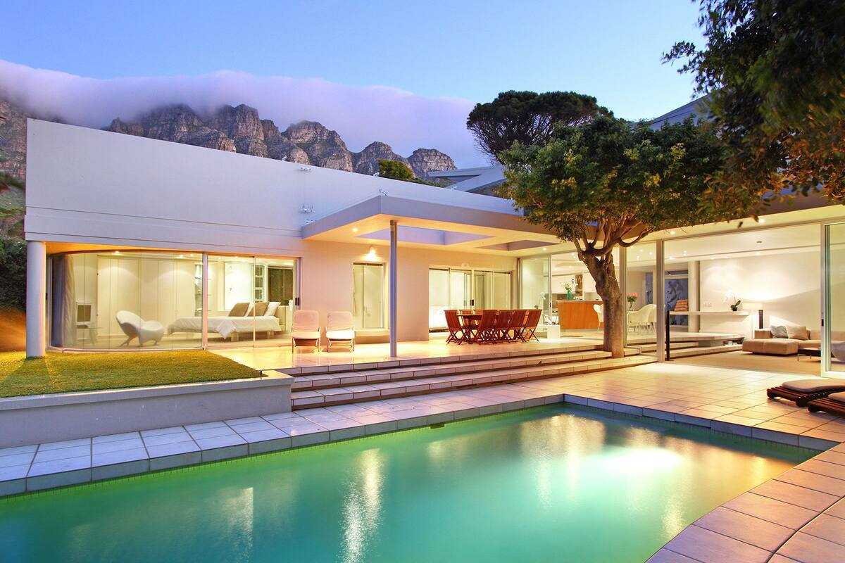 A modern house with a swimming pool, glass doors, and a dining area.