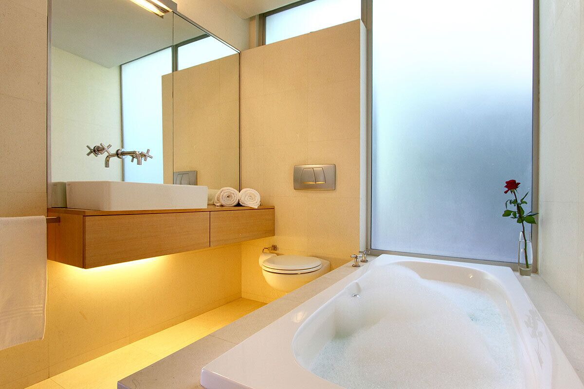 Une salle de bain moderne avec une grande baignoire, des toilettes et un lavabo avec un miroir au-dessus.