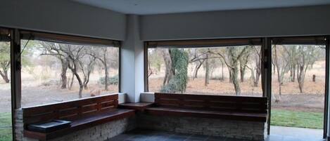 Una habitación amplia con ventanas grandes, un banco de piedra y suelo de baldosas.