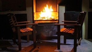 A fireplace with two wooden chairs facing it. - Foreva Wild (Hammanskraal)