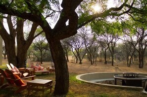 An outdoor seating area with Adirondack chairs and a circular fire pit. - Foreva Wild (Hammanskraal)