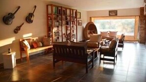 A cozy living room with a fireplace, a bookshelf, and a dining area. - Foreva Wild (Hammanskraal)