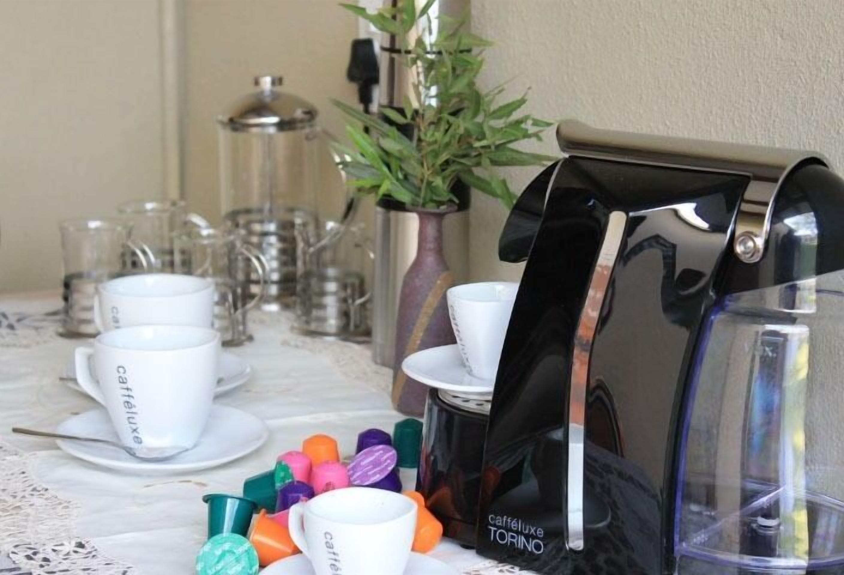 Una mesa con tazas blancas etiquetadas como "cafféluxe" y una cafetera.