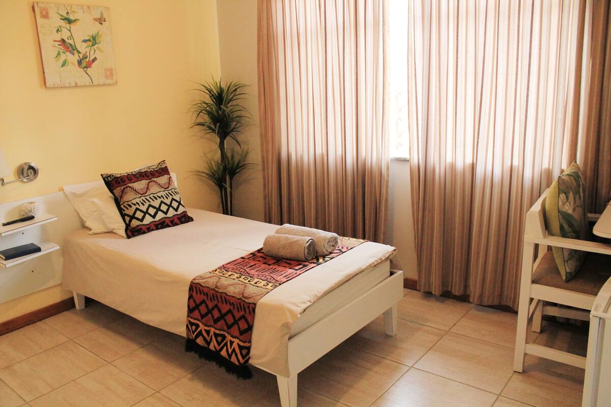 A neatly arranged bedroom with a bed, bedside table, and a chair.