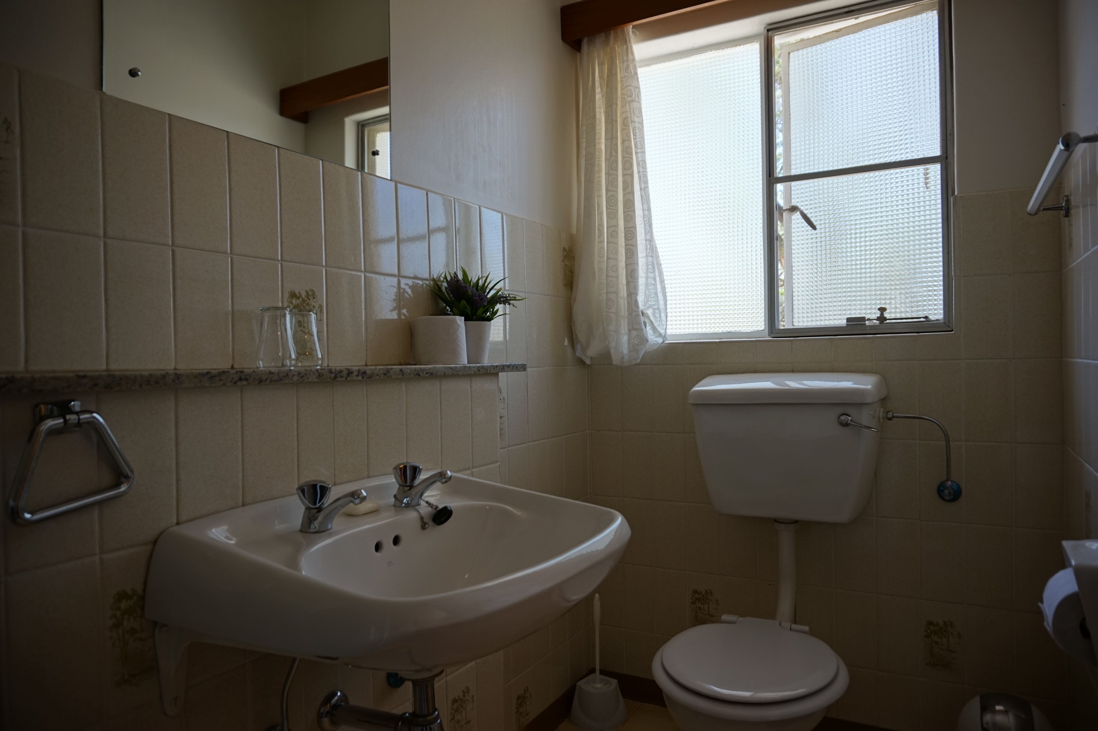 Een badkamer met een wastafel, toilet en raam.