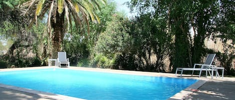 Una piscina al aire libre, sillones reclinables de piscina