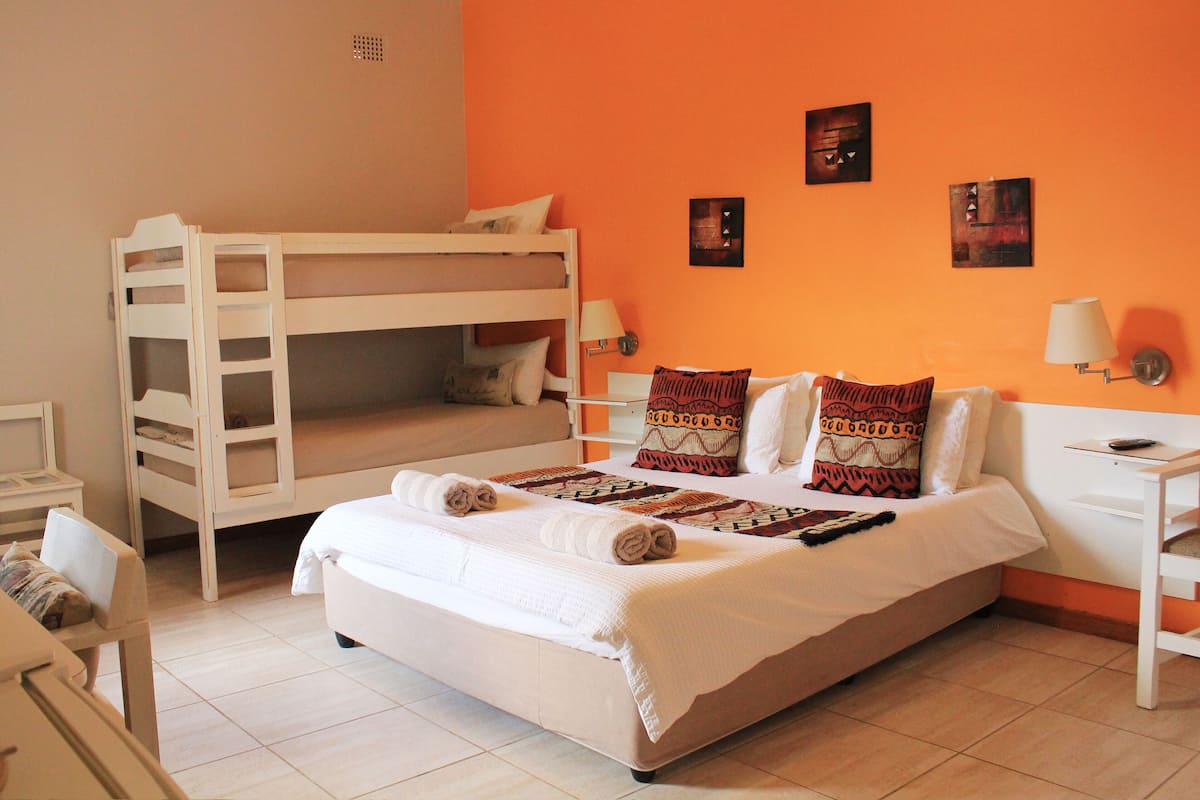 A room with a bunk bed, a single bed, and a desk.