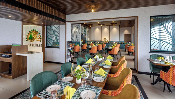 Un restaurant doté d’une longue table à manger, de nombreuses chaises et d’un comptoir d’accueil.