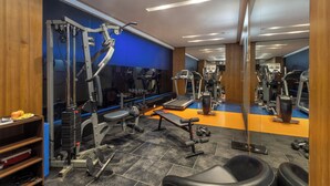 Une salle de sport équipée de matériel d’exercice, d’un tapis de course et d’un mur recouvert de miroirs.