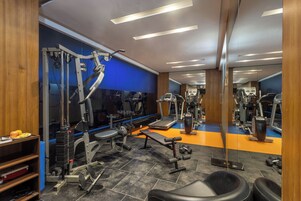 Un gimnasio con equipo de ejercicio, una cinta de correr y un espejo grande.