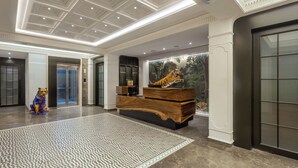 Un hall d’entrée spacieux, doté d’un tapis à motifs, d’un comptoir de réception en bois et d’une grande fresque représentant un tigre.