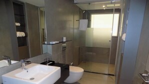 Une salle de bain moderne avec un grand miroir, un lavabo blanc et des toilettes.